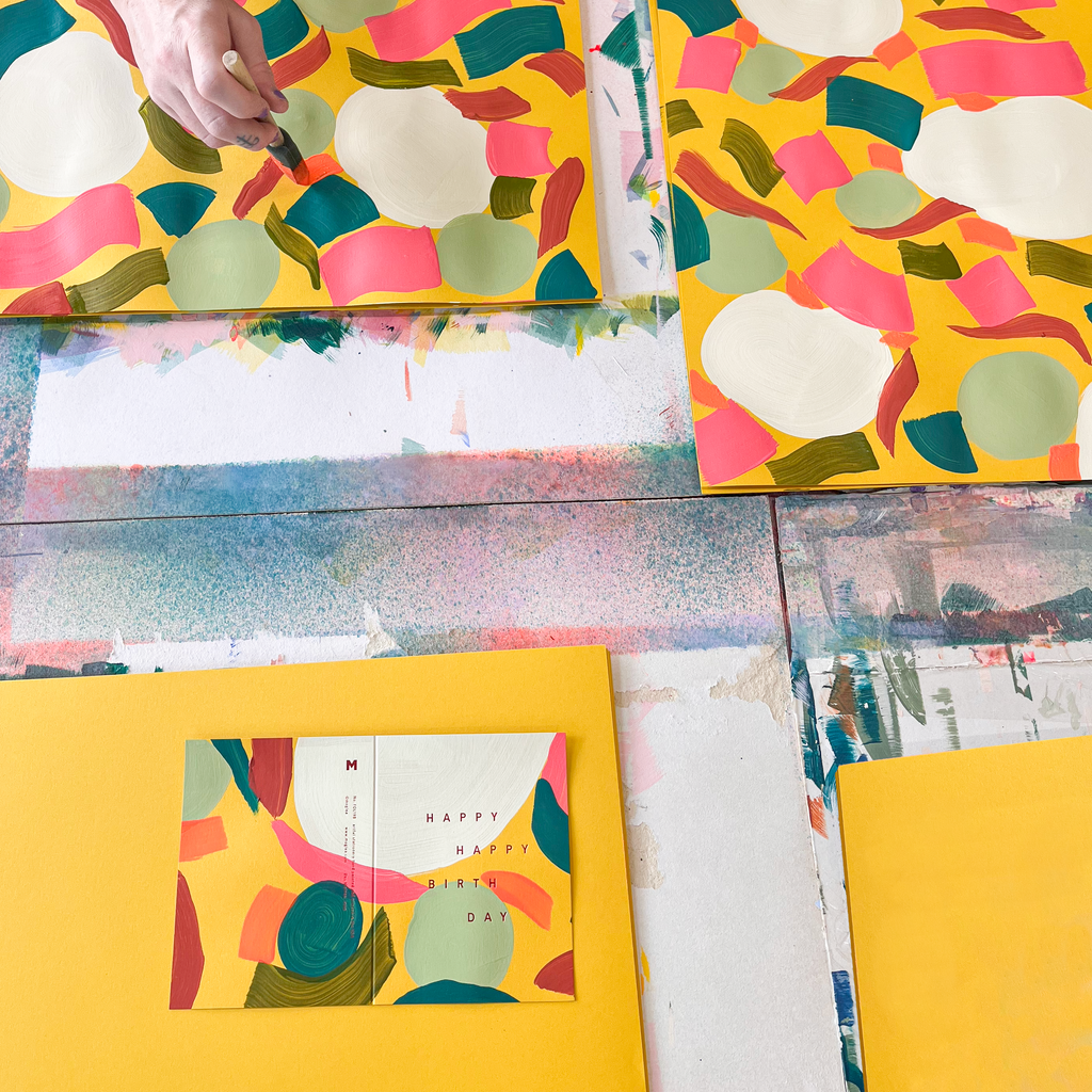 Colorful abstract art pieces on a table with a person holding a red cup.
