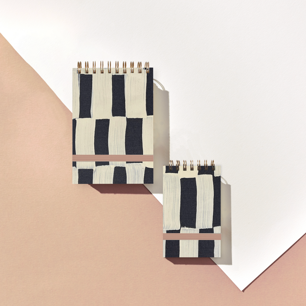Two black and white striped notebooks on a geometric background