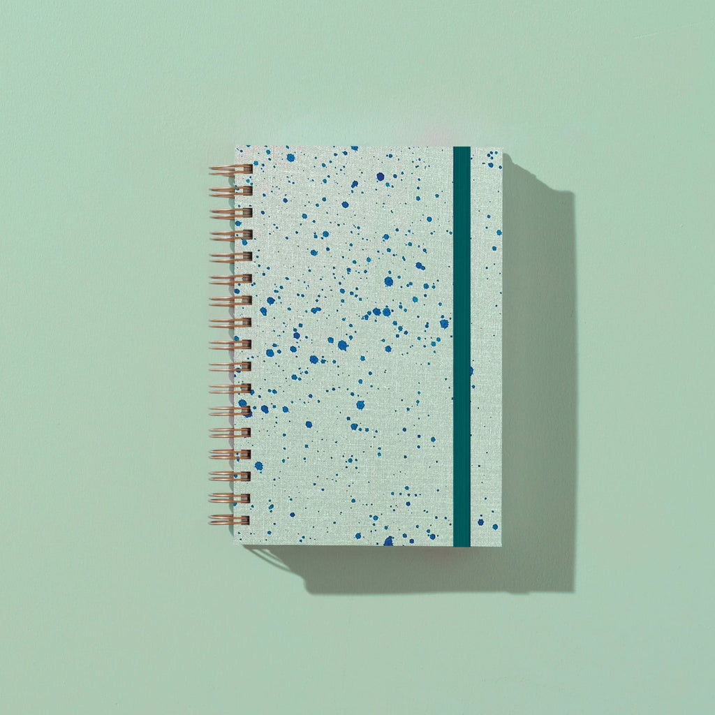 Speckled notebook with a green stripe on a light green background