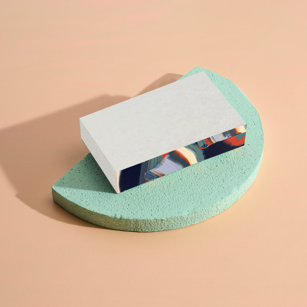 Notepad on a green wedge-shaped stand against a beige background