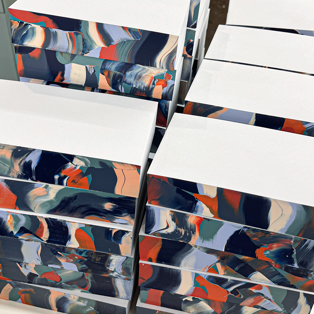 Stacks of notepads with abstract pattern on a white surface in an indoor setting