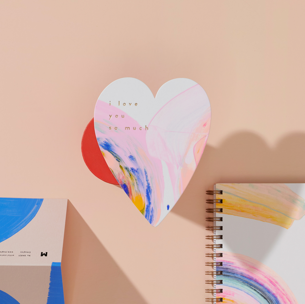 Heart-shaped card with 'I love you so much' text on a painted abstract background